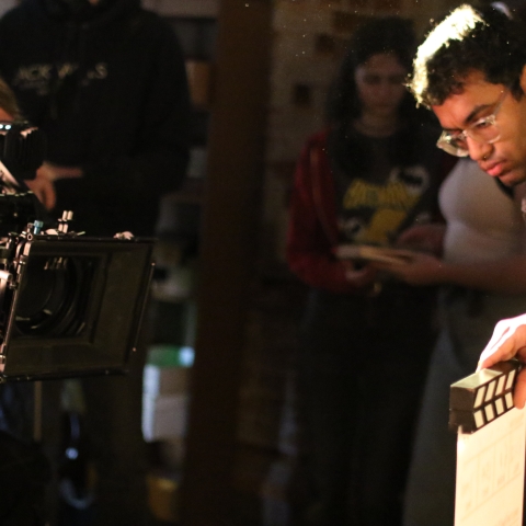 students using a film camera and a clapperboard whilst filming their student film