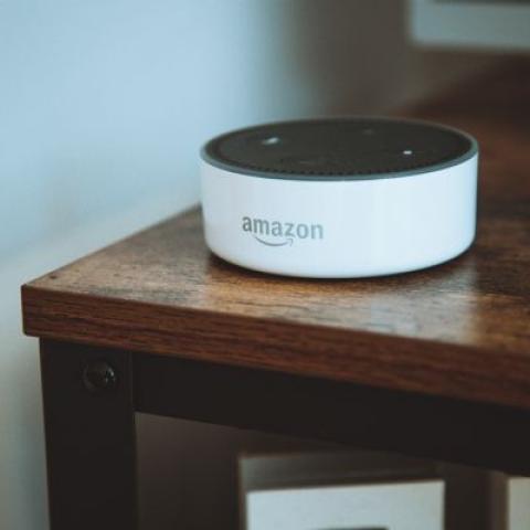 A white Amazon Alexa on top of a brown wooden table