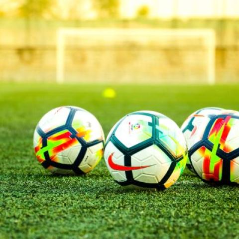 Three footballs on a football pitch