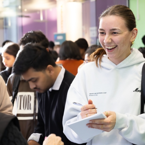 A female student is speaking to a member of staff in the Careers and Employability Centre while writing notes.