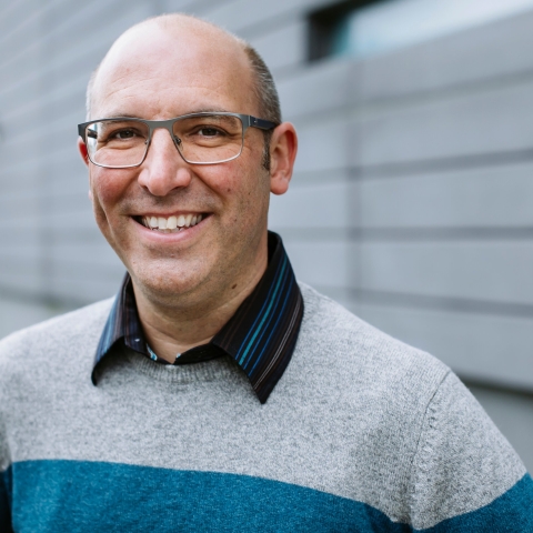 Professor George Burrows smiling in front a blurred out background