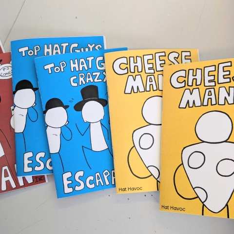 A set of colourful indie‑style comic books laid out on a table, each with bold titles and simple cartoon characters on the covers.