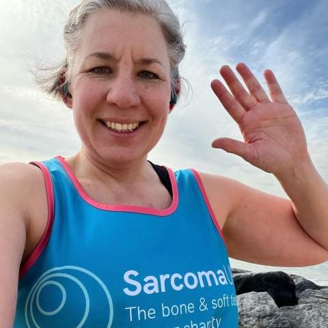 Nicola Crowson from the University of Portsmouth smiling at a camera for a selfie while running in a Sarcoma UK top during a fundraising event