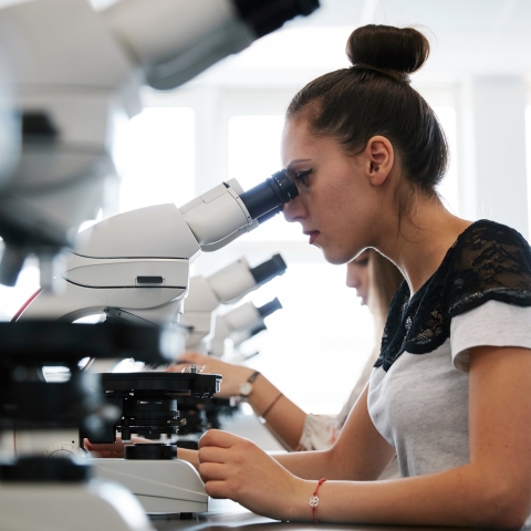 Female student using microscope