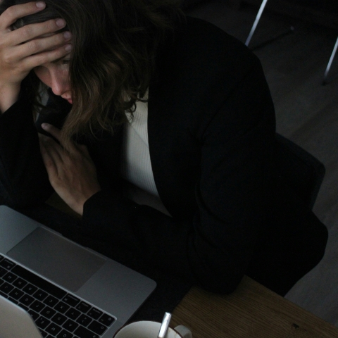 woman sitting by laptop in discomfort 