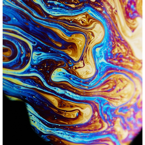 A close‑up of swirling blue, purple, yellow, and brown patterns creating a marbled, fluid abstract surface.