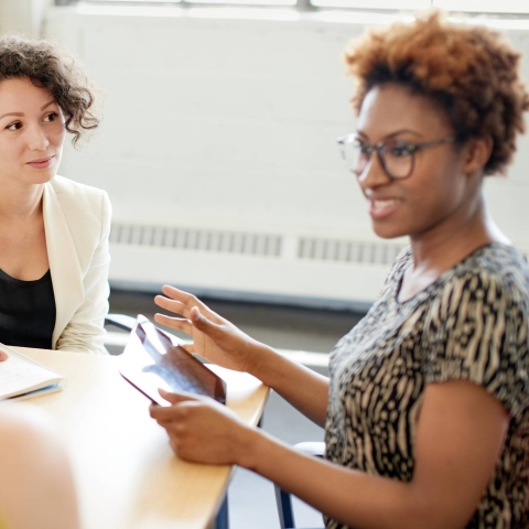 An academic talking to a student sat at a desk