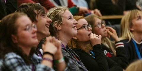 Image of an audience, seated, watching and listening to a presention