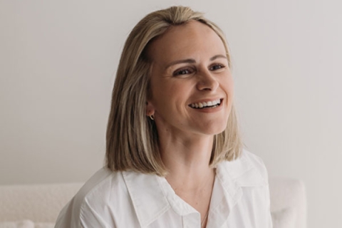 Graduate, Natty, has blonde hair and is wearing a white shirt on a photoshoot - in the photo, she is smiling off camera