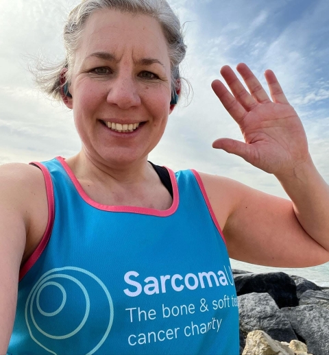 Nicola Crowson from the University of Portsmouth smiling at a camera for a selfie while running in a Sarcoma UK top during a fundraising event