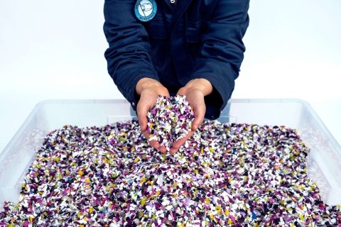 Hands holding up small pieces of coloured plastic.