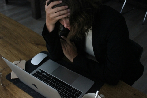 woman sitting by laptop in discomfort 