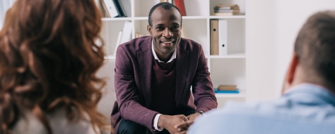 Smiling counsellor meeting with two people in an office.