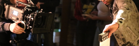 students using a film camera and a clapperboard whilst filming their student film