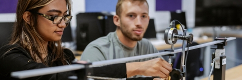 Two students take down measurements of weight using digital newton-metre at Technology Facilities