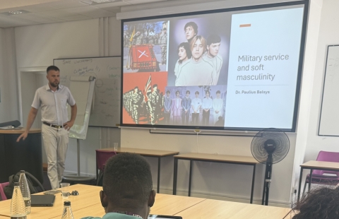 Lecturer standing infront of a presentation to a class of attendees