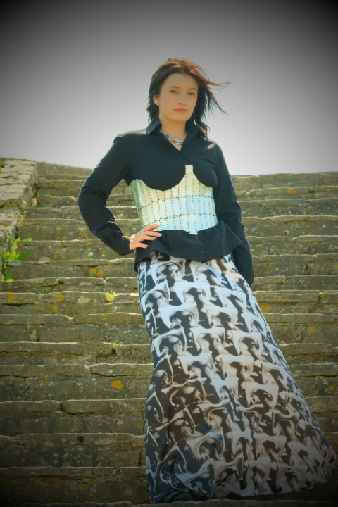 Image of model wearing a garment with a silver corset and flowing dress - standing on concrete stairs