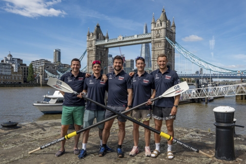 A team of rowers holding oars in front of Tower Bridge, London