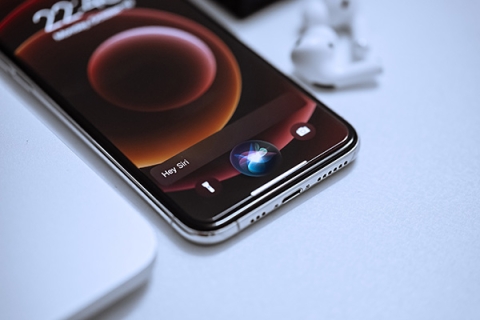 An iPhone on a white surface. The phone says 'Hey Siri' along the bottom