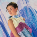 Model wearing a pastel yellow, purple and blue garment infront of blue and white LED screens