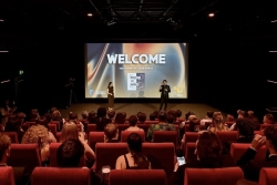 An audience in red chairs facing a screen showing a British Film Institute showcase