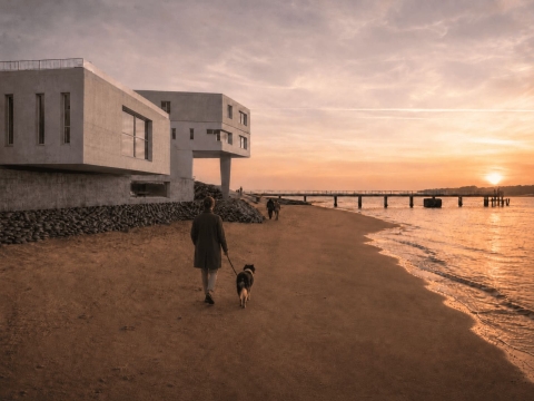 A modern concrete building overlooking the beach at sunset, with people walking along the shoreline and a pier extending into the sea.