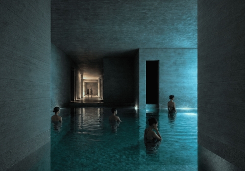 People standing in a tall, minimal concrete bathing space with soft blue light reflecting off the water.