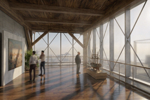 A bright exhibition hall with wooden floors, tall windows, and framed artworks displayed along clean white walls.