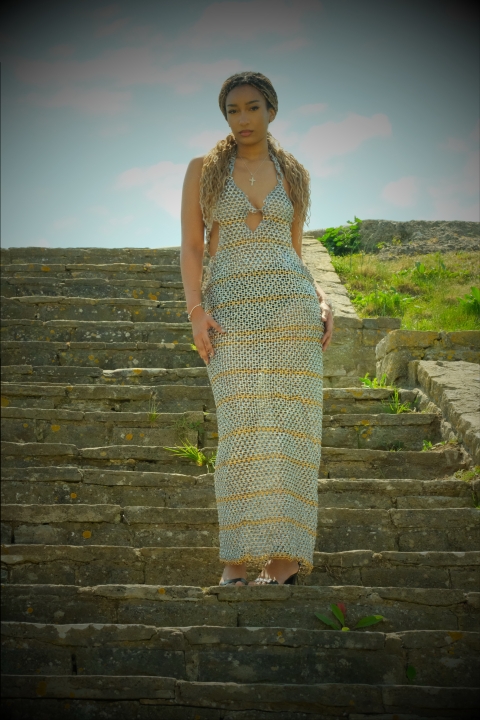 Student wearing silver garment whilst standing on concrete looking stairs -  image has a filter to make it look a bit more old fashioned