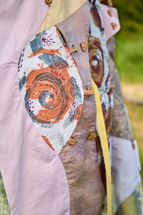 Close up of Hannah Hatchards garment - featuring a swirly design in orange and blue