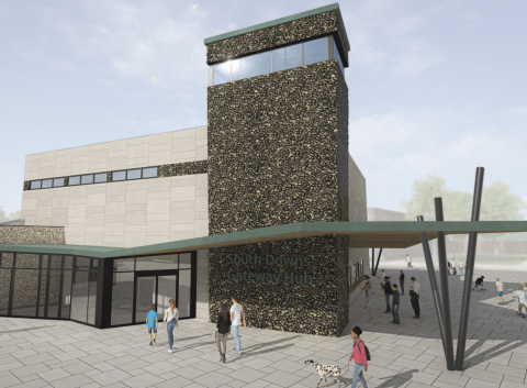 Modern building with a tall tower, pale stone cladding, angled columns at the entrance canopy, and people walking across the open plaza in front of the South Downs Gateway Hub.